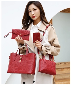 Detail of red crocodile pattern 4-piece handbag set shown on a model with a beige coat