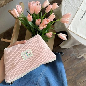 Close-up of pink corduroy makeup bag with textured fabric and vintage woven label detail