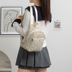 Detail of floral canvas backpack featuring orange flower pattern and woven straps