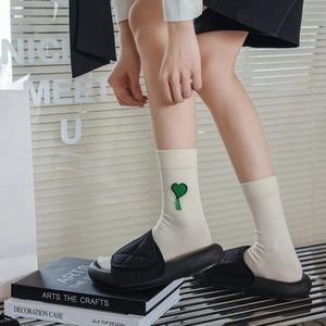 Dettaglio calzini beige con ricamo a cuore verde e sandali neri con suola a piattaforma