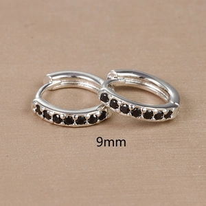 Macro shot of 9mm silver hoop earrings with round black zircon stones on wood surface