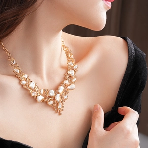 Detailed close-up of champagne teardrop rhinestones on a golden necklace set