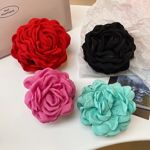 Detailed flat lay of four fabric rose hair claws in red, black, pink, and mint green