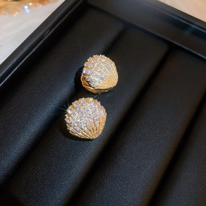 Detail of shell-shaped earrings with gold plating and white cubic zirconia on leather box