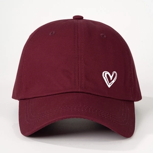 Detail of white heart embroidery on a burgundy cotton baseball cap with twill texture