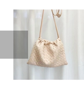 Close-up of beige woven leather texture and drawstring closure on the shoulder bag