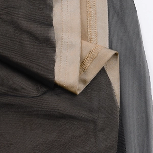 Macro shot of black mesh fabric with gold trim and intricate stitching details