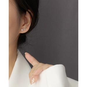 Macro shot of three sparkling S925 silver star earrings worn along the ear lobe