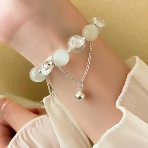 Minimalist beaded moon bracelet with crystal beads and silver bell charm on wrist