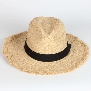 Chapeau de soleil en paille avec bords effilochés et ruban noir sur fond blanc neutre