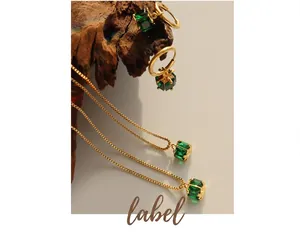 Detailed shot of emerald zircon jewelry set with necklaces and earrings on rustic wood