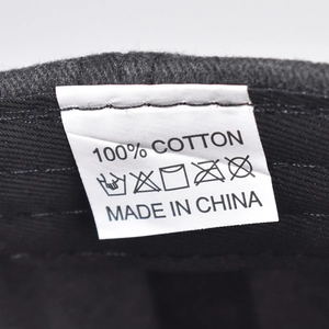 Macro shot of 100% cotton material tag and care instructions inside the baseball cap