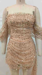 Detailed close-up of champagne gold sequin fabric with ruched texture on a mini dress