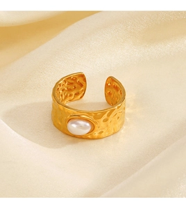 Detailed macro view of gold hammered texture ring with pearl inlay on silk background
