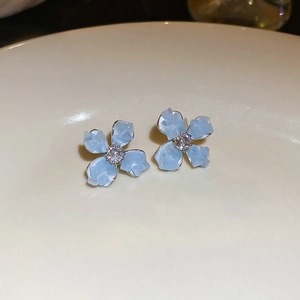 Macro shot of light blue crystal floral earrings with silver base on ceramic plate