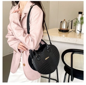 Détail du sac à main noir à texture crocodile avec accents dorés et bandoulière amovible