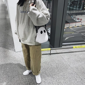 Ghost shaped white crossbody bag with cute eyes and black zipper strap shown on model