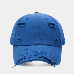 Detailed close-up of distressed ripped edges on a vintage navy blue cotton baseball cap
