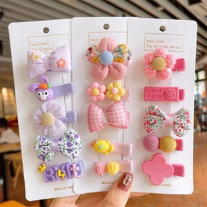 Close-up of 15-piece girls' hair clip set with cute fabric bows and resin animal shapes