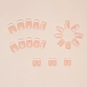 Detailed flat lay of nude pink press-on nails with white floral patterns and French tips