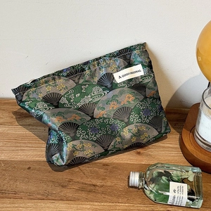Detail of vintage style jacquard fabric makeup bag with golden floral fan pattern