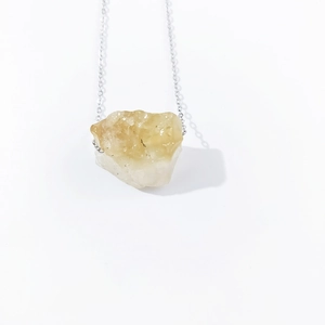Macro shot of irregular natural raw citrine quartz stone pendant on a silver thin chain