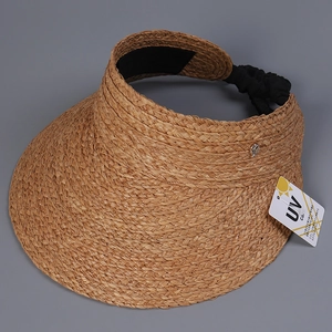 Detail of woven raffia sun hat with elastic strap and metal bee accent for UV protection