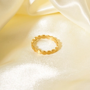 Macro shot of gold-plated stainless steel ring with wavy edges on silk fabric