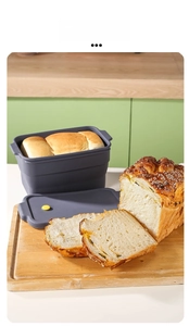 Close-up of collapsible grey silicone rectangle bread mold with lid on wooden board