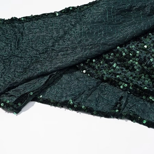 Detailed view of dark green pleated fabric featuring shimmering sequins decorations