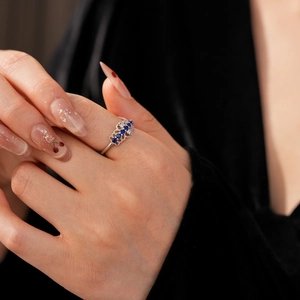 Gros plan d'une bague couronne avec zircons bleus et blancs sur le doigt d'un mannequin