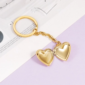 Macro view of gold heart locket keychain open to reveal dual inner photo compartments