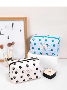 Detail of quilted floral makeup bags in blue and black with embroidered fabric labels