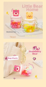Detail showing cartoon bear liquid quicksand keychain hanging on a stylish handbag