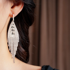 Close-up of elegant silver tassel earrings with sparkling rhinestones on a model
