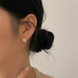 Close-up of minimalist silver 925 stud earrings featuring a double-line design on a model