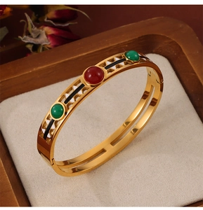 Detail of vintage gold plated bangle with hollow geometric patterns and colorful gemstones