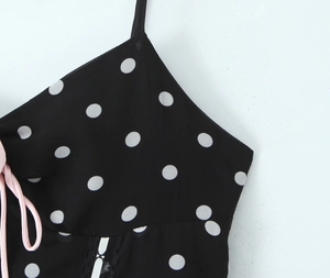 Detail eines schwarzen Polka-Dot-Kleides mit rosa Schleifenband und schwarzem Spitzenbesatz