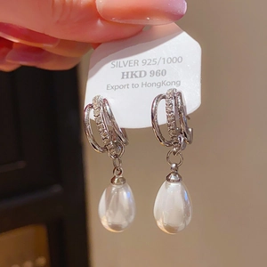 Macro detail of silver 925 bow pearl earrings featuring sparkling zircon inlay accents