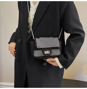 Detail of a sparkling black rhinestone crossbody bag with silver chain strap on model