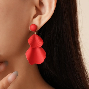 Close-up of red multi-layered petal earrings worn by a model for a creative floral look