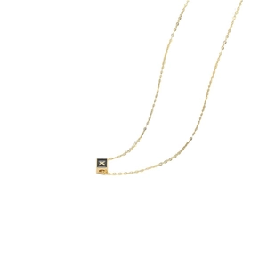 Minimalist gold necklace featuring a square black cube pendant with letter X detail