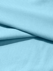 Macro shot of sky blue waffle weave fabric showing premium textured cotton structure