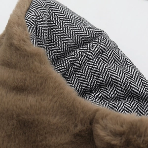 Macro detail of brown faux fur lining and black herringbone wool fabric texture