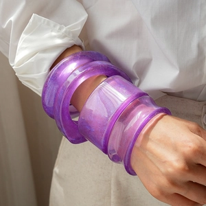 Stackable purple resin bangle set with glitter details on a natural background