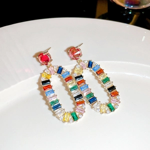 Macro shot of oval drop earring featuring vibrant rainbow crystals and red stone detail