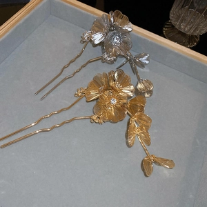 Detailed macro view of gold and silver flower hairpins with crystal centers on velvet tray