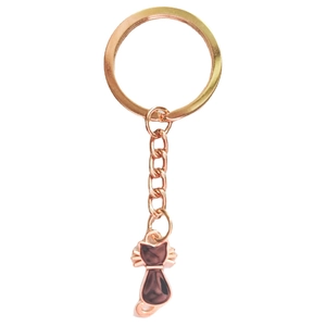 Detail of rose gold cat keychain featuring dark enamel filling on a minimalist metal pendant