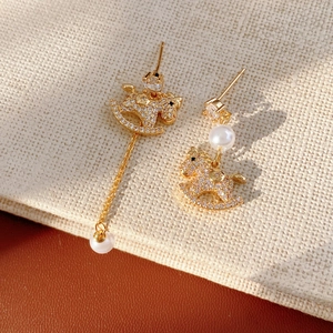 Detailed view of gold rocking horse earrings with asymmetric pearls and cubic zirconia
