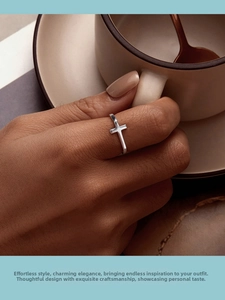 Close-up of minimalist S925 sterling silver cross ring worn on finger with coffee cup